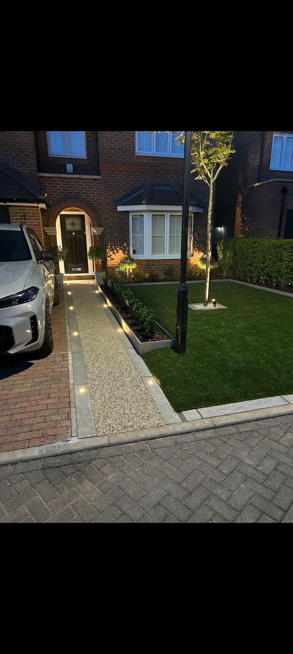 Front garden landscaping with new turf, paved path and lighting by Ground Up Landscaping
